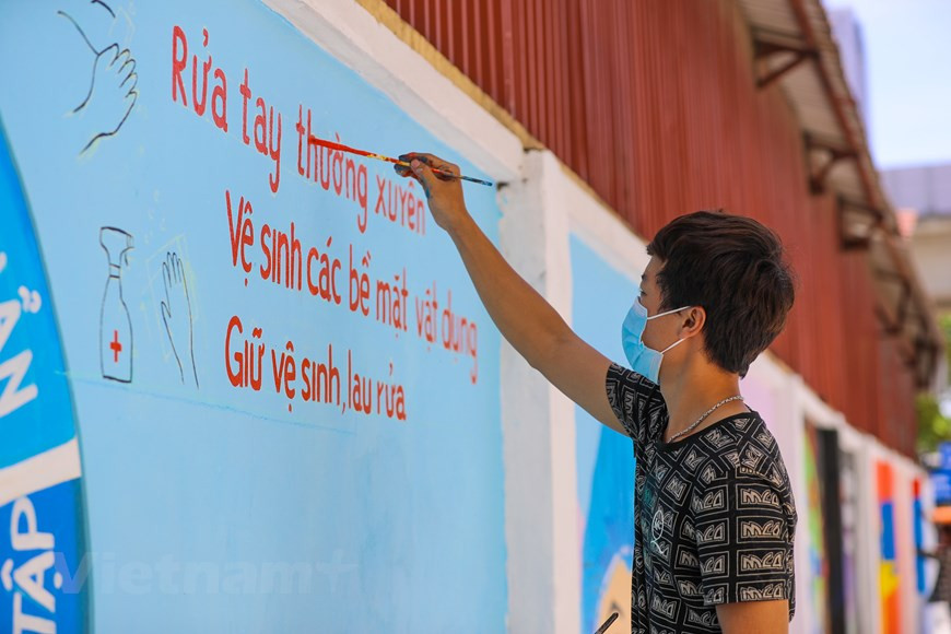 L'antenne de l'Union de la jeunesse communiste Hô Chi Minh de l'arrondissement de Ha Dông de Hanoï a choisi la rue Vu Trong Khanh pour faire ces peintures murales anti-Covid-19. Les peintures murales constituent un point remarquable attirant les gens. Auparavant, le président du Comité populaire de Hanoi, Chu Ngoc Anh, a signé un télégramme urgent autorisant d'interdire temporairement toutes les activités non essentielles pour contrôler la propagation de l’épidémie de Covid-19. Les habitants de la capitale présentant des symptômes de fièvre, de toux et de difficultés respiratoires sont appelés à venir aux hôpitaux pour consultation et traitement, en vue d’empêcher la propagation de l’épidémie de Covid-19. Photo : VietnamPlus