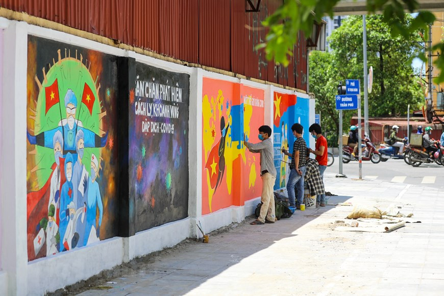 Le jeune peintre Nguyên Quang et ses collègues sont les artistes de rue qui ont mené ce projet de peintures murailles en grand format, en coordination avec l'antenne de l'Union de la jeunesse communiste Hô Chi Minh de l'arrondissement de Ha Dông de Hanoï. Des peintures murales, dont le thème porte sur la lutte contre le Covid-19, sont situées à la jonction des rues Trân Phu et Vu Trong Khanh. Elles attirent beaucoup l'attention des passagers. Cet ouvrage artistique a nécessité une semaine de travail et est bien apprécié par les populations. Chaque peinture a son propre contenu à propos de la lutte contre l’épidémie de Covid-19. Photo : VietnamPlus