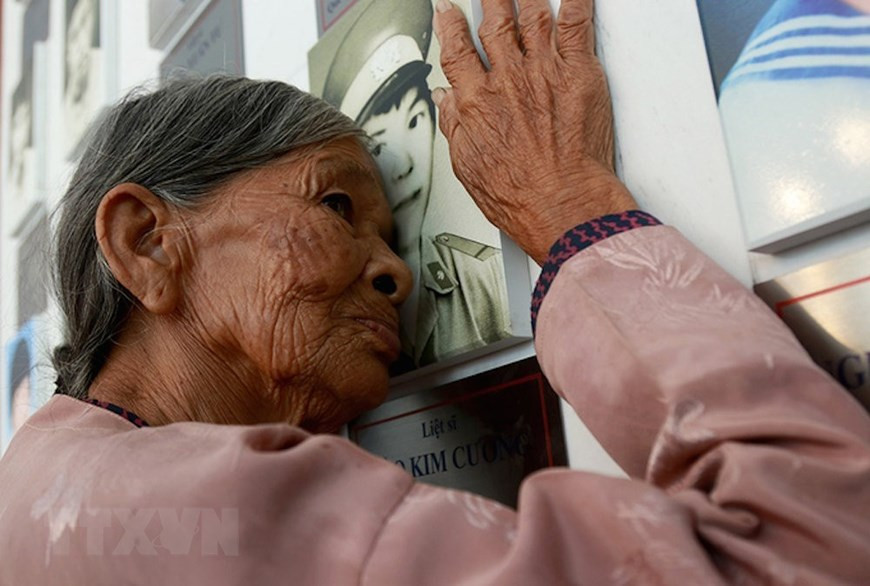  Ha Thi Liên (du district de Can Lôc, province de Ha Tinh), mère du martyr Dao Kim Cuong, s'embrasse sur la photo de son fils au monument des soldats tombés à Gac Ma dans la zone commémorative à Khanh Hoa. Photo : VNA