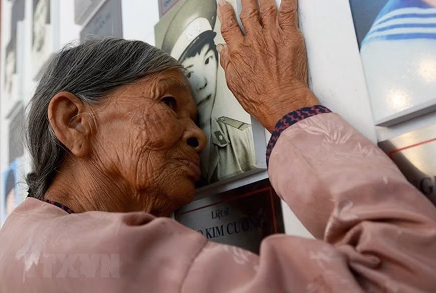  Ha Thi Liên (du district de Can Lôc, province de Ha Tinh), mère du martyr Dao Kim Cuong, s'embrasse sur la photo de son fils au monument des soldats tombés à Gac Ma dans la zone commémorative à Khanh Hoa. Photo : VNA
