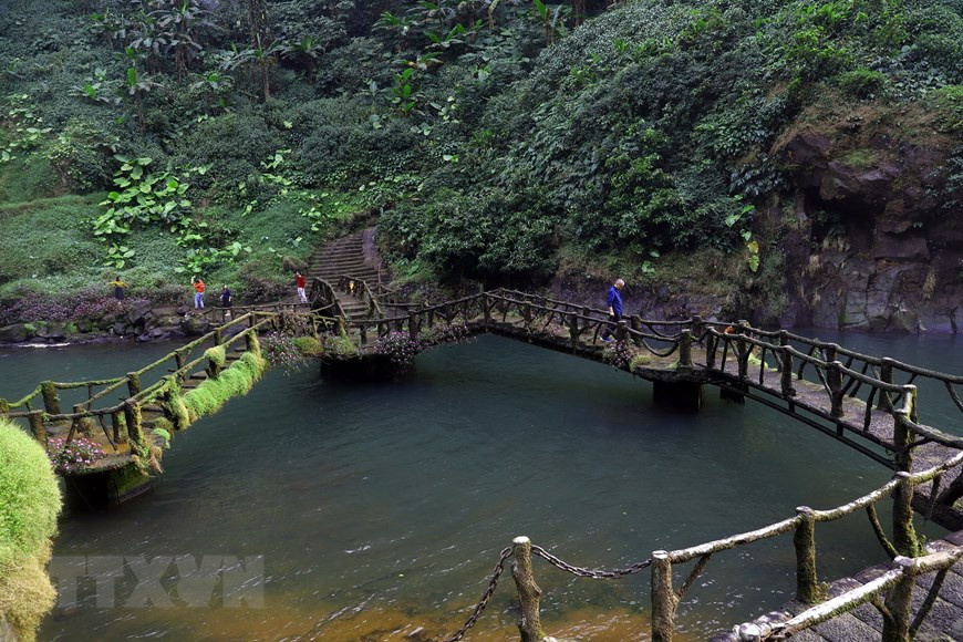 Le petit pont relie les deux rives au pied de la cascade. Photo : VNA