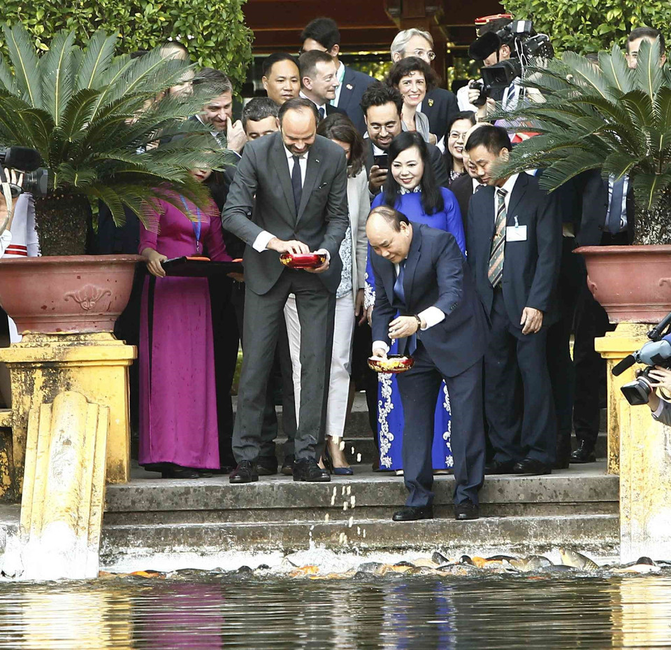 Les deux Premiers ministres Édouard Philippe et Nguyên Xuân Phuc se sont arrêtés devant un bassin en face de la maison sur pilotis du Président Hô Chi Minh pour nourrir les poissons.