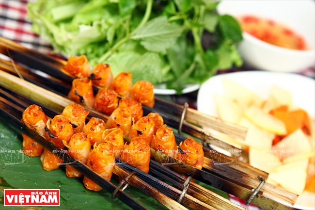 Rouleaux de crevettes grillés. Le plat est servi avec la sauce aigre-douce, des herbes aromatiques, ​des achards et des tranches de figues salées (Ficus racemosa).