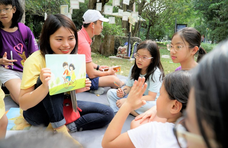 Une volontaire initie les enfants aux activités de protection de l'environnement. Photo: Vietnam+