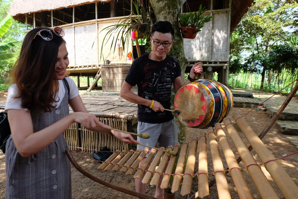 Des jeunes tentent de jouer des instruments de musique traditionnels des Xo Dang. Photo: VNA