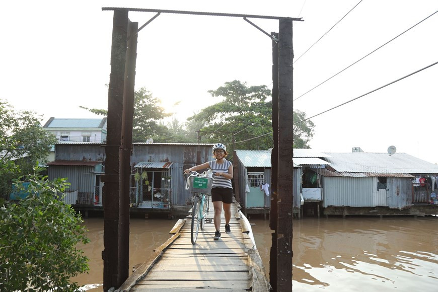  Les touristes prennent souvent le vélo pour traverser les ponts en bois rudimentaires. Photo: Vietnam+ 