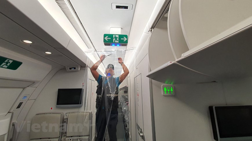 Des parties de la section des passagers sont séparées par des rideaux en plastique. Un vol est sans précédent car le taux de patients de COVID-19 à bord était supérieur à 50% du nombre total de passagers. Ayant de nombreuses expériences dans le rapatriement de citoyens vietnamiens de pays instables comme la Libye en 2011 et en 2014 ou le Japon après le tremblement de terre et le tsunami en 2011, Vietnam Airlines a minutieusement travaillé avec les ministères et secteurs concernés, tels que le ministère des Affaires étrangères et le ministère de la Santé, pour discuter des préparatifs et faire face aux cas suspects d'infection à bord. Photo: VietnamPlus