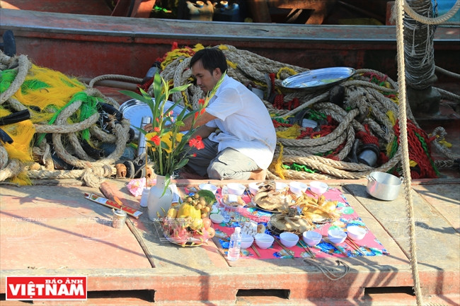 Un pêcheur prépare des offrandes sur son navire. 