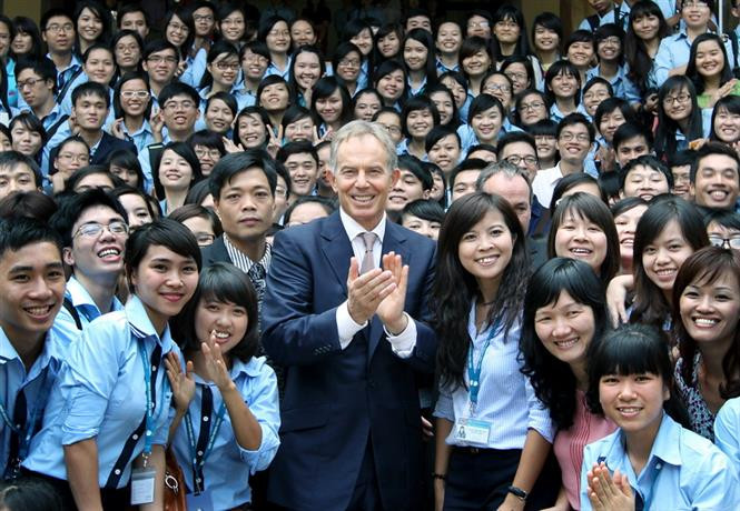 Des étudiants de l’Académie de la diplomatie de Hanoi accueillent l’ancien Premier ministre Tony Blair à visiter l’école le 15 octobre 2012.