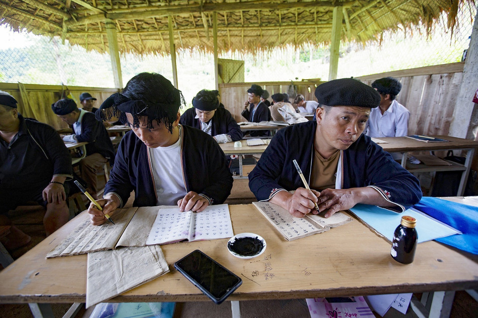 Ly Van Henh enseigne l'écriture Nom - Dao à des élèves de différents âges. 