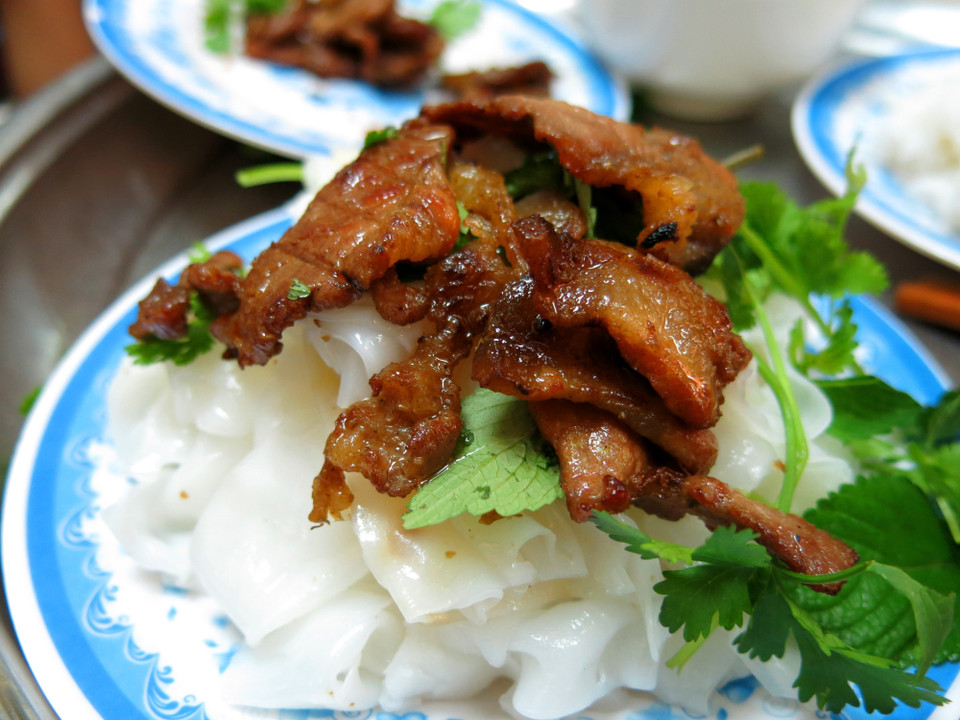 La pâte cuite est ensuite roulée avec de la viande hachée et des champignons noirs, trempée dans de la sauce de poisson et mangée avec des oignons frits croustillants.