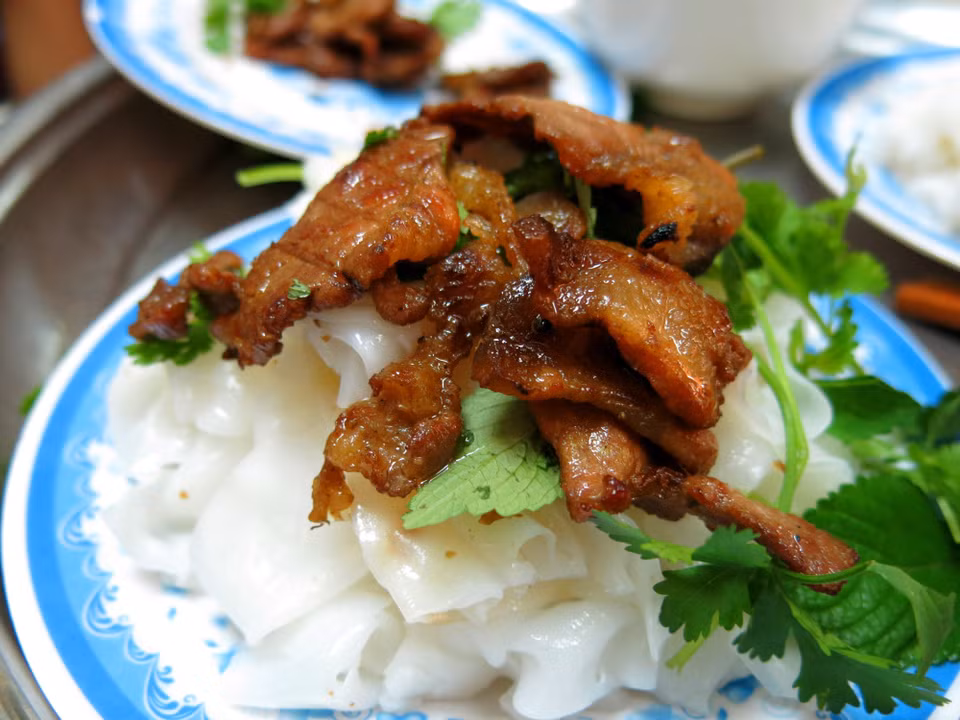 La pâte cuite est ensuite roulée avec de la viande hachée et des champignons noirs, trempée dans de la sauce de poisson et mangée avec des oignons frits croustillants.