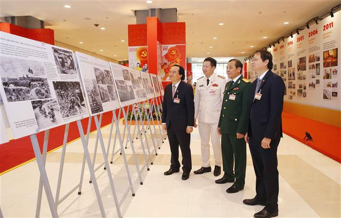 Plusieurs délégués apprécient les belles photos sur des moments historiques de la Révolution vietnamienne sous la direction du Parti. Photo: VNA