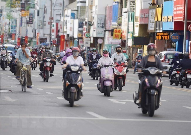 Les habitants circulant dans la rue Phan Dinh Phung, district de Phu Nhuan, portent le masque pour prévenir l'épidémie de COVID-19. Photo: VNA