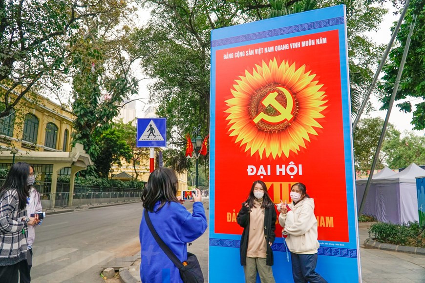 Les jeunes aiment prendre des photos devant de grandes affiches. Photo: Vietnam+
