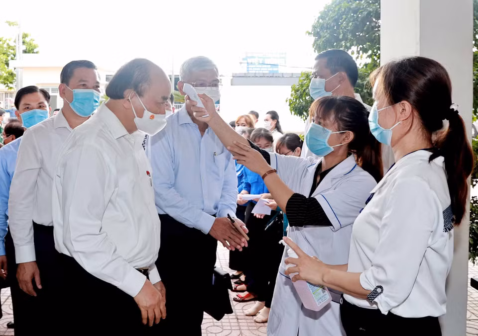 Le président Nguyen Xuan Phuc fait vérifier leur température corporelle avant de participer à la réunion avec des électeurs de la commune de Trung Chanh, district de Hoc Mon. Photo: VNA