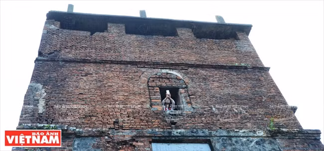 Un jeune homme essayant de prendre une photo de Danang à partir d'une fenêtre de la tour de Hai Vân Quan. 
