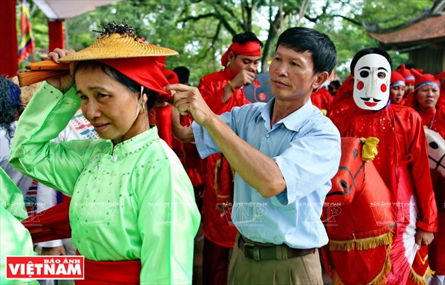 L'artisan aide une artiste à préparer des costumes avant de présenter la danse Ngo Quoc lors du festival Lam Kinh 2018.
