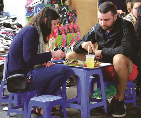 Un couple de touristes étrangers déguste le ''nôm bo khô'' (salade de légumes hachés à la viande de bœuf séché, assaisonné de papaye verte râpée).