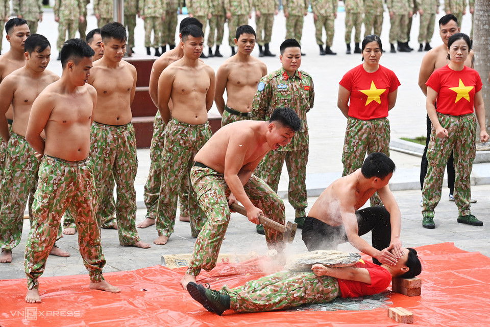 Cassage de briques placées sur le corps d'une femme soldat. Photo: vnexpress