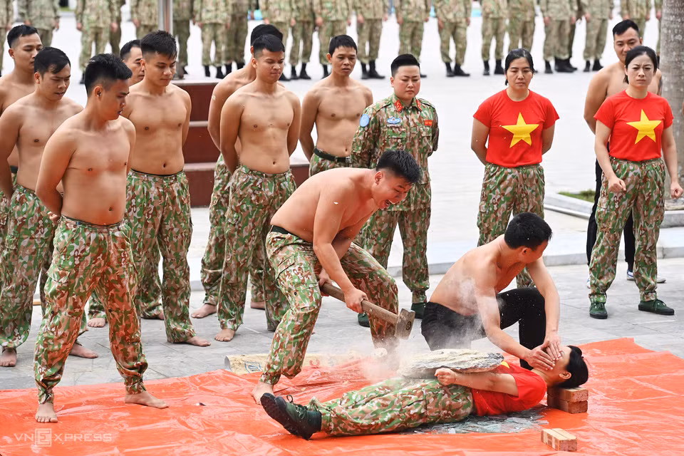 Cassage de briques placées sur le corps d'une femme soldat. Photo: vnexpress