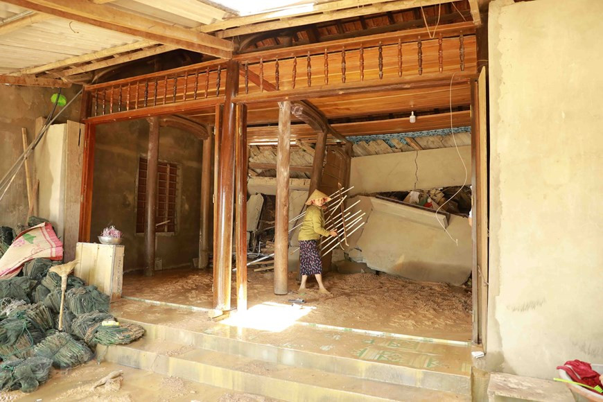 Une femme se prépare pour fuir la maison endommagée par un glissement de terrain. Photo: VNA