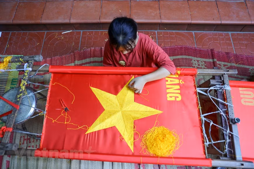 La couture est beaucoup plus simple que la broderie d'un drapeau. En une journée, des centaines de drapeaux peuvent être fabriqués à l'aide de machines à coudre, alors qu'il faut des semaines aux brodeurs pour fabriquer le même volume. Broder un drapeau est un processus laborieux et chronophage qui passe par plusieurs étapes telles que le choix des tissus, la mesure des tissus, la découpe des tissus et la broderie de l'étoile dorée à cinq branches, entre autres. À la suite d'un processus minutieux et long, chaque drapeau brodé est vendu à un prix d'au moins 300 000 dôngs (12,94 dollars américains). Photo: VietnamPlus