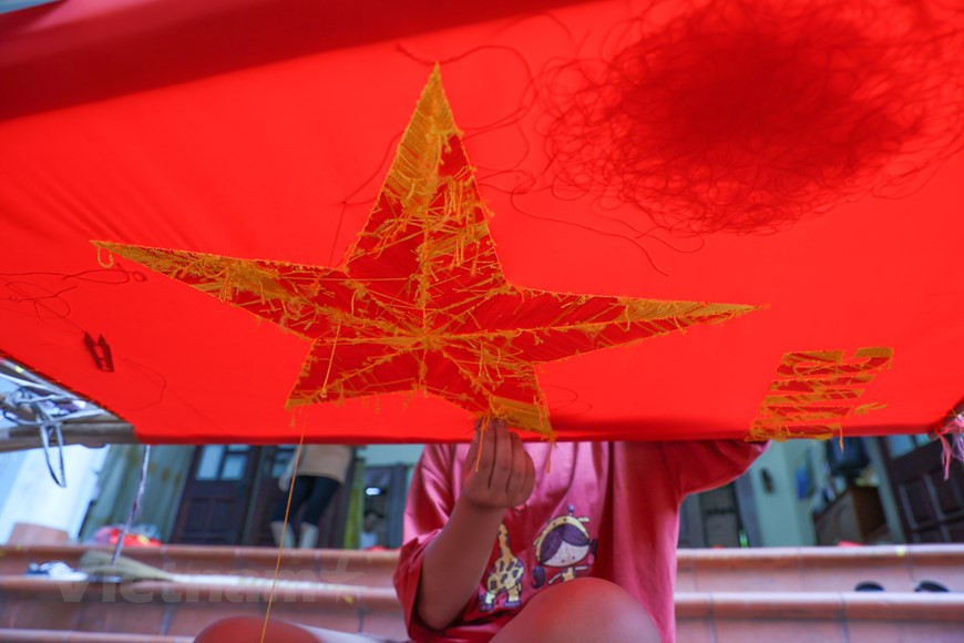 L'étape la plus importante dans la fabrication d'un drapeau artisanal est de choisir les bons matériaux. Le tissu doit être du satin acheté à La Khe - un village artisanal de tissage de tissus renommé dans l’arrondissement de Ha Dong à Hanoï. Le satin doit être épais, rouge vif et durable. Les fils, quant à eux, sont achetés à Trieu Khuc, un autre village artisanal de tissage de tissus renommé dans la commune de Tan Trieu, arrondissement de Thanh Tri à Hanoï. Cependant, l'étape la plus difficile est d'insuffler une vie à chaque produit, qu'il soit grand ou petit, imprimé ou brodé. Photo: VietnamPlus