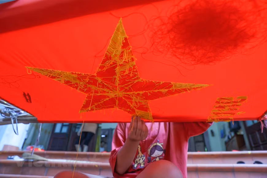 L'étape la plus importante dans la fabrication d'un drapeau artisanal est de choisir les bons matériaux. Le tissu doit être du satin acheté à La Khe - un village artisanal de tissage de tissus renommé dans l’arrondissement de Ha Dong à Hanoï. Le satin doit être épais, rouge vif et durable. Les fils, quant à eux, sont achetés à Trieu Khuc, un autre village artisanal de tissage de tissus renommé dans la commune de Tan Trieu, arrondissement de Thanh Tri à Hanoï. Cependant, l'étape la plus difficile est d'insuffler une vie à chaque produit, qu'il soit grand ou petit, imprimé ou brodé. Photo: VietnamPlus