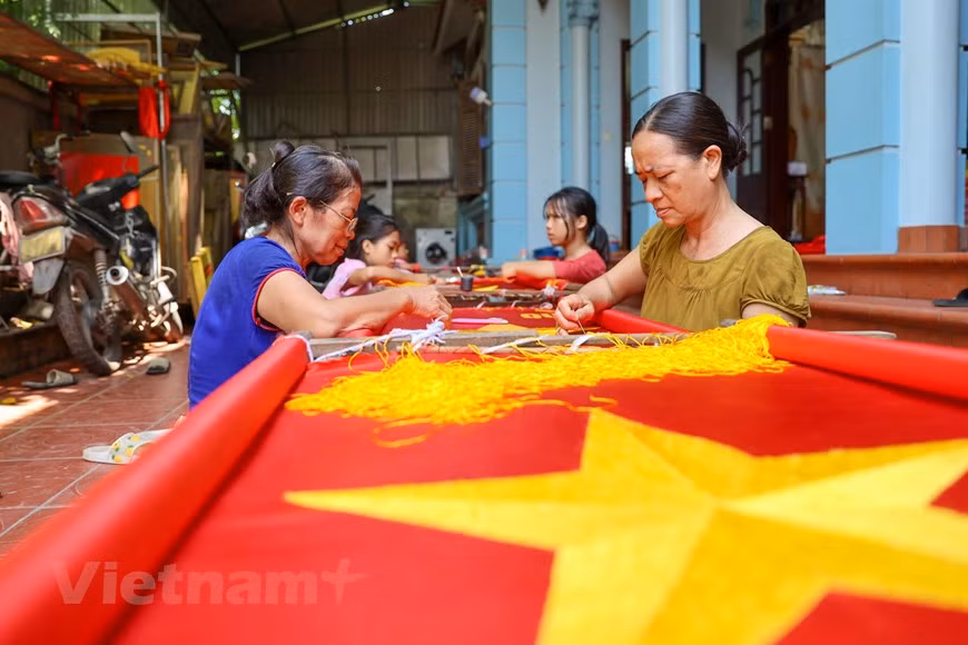 Au cours de la dernière décennie, la demande de drapeaux nationaux a augmenté et sa famille est devenue plus occupée en conséquence. À l'approche des événements nationaux, le drapeau national (un drapeau rouge avec une étoile jaune à cinq branches au centre) est en forte demande et les villageois de Tu Van entrent au sommet de leur production de drapeau. Pour un brodeur vétéran comme Vuong Thi Nhung, il faut souvent entre 3 et 5 jours pour terminer la broderie d'un drapeau. Pour les amateurs, cela peut prendre jusqu'à une semaine. Broder le drapeau national est un travail exigeant qui demande beaucoup de finesse et de minutie dans chaque point, car les produits finaux sont pour des événements importants. Photo: VietnamPlus