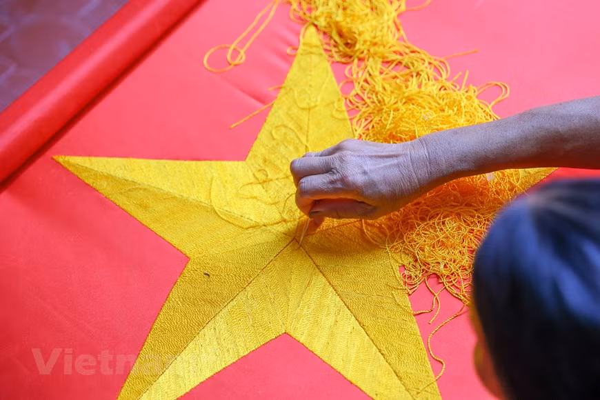 Le village compte 10 familles engagées dans la production de drapeaux. Certains se spécialisent dans la broderie. Certains confectionnent des drapeaux nationaux pour les nouvelles années scolaires, les célébrations de la Fête nationale et de certains autres occasions. Certains spécialisés dans la fabrication des bannières et des affiches pour les principaux festivals et jours fériés, et même pour encourager l'équipe nationale de football du Vietnam. Bien qu’il n’y ait pas autant de familles dans le village qui fabriquent actuellement des drapeaux, la vente des produits leur fournit un revenu stable et une chance de démontrer leur patriotisme et leur fierté nationale. Photo: VietnamPlus