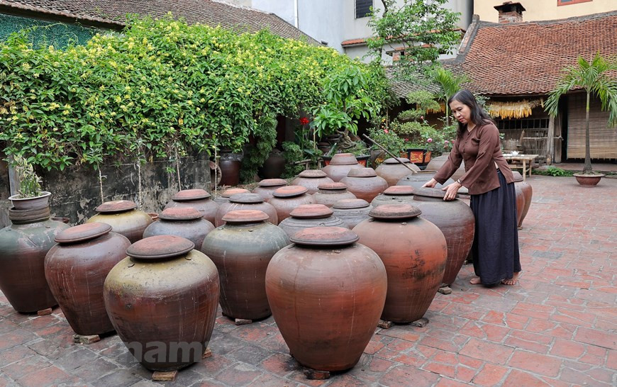 Dès la petite porte d’entrée de l’ancienne maison en latérite de Hà Huu Thê, on sent déjà l’odeur fermentée de la sauce soja. Dans une grande cour de 50 m², une dizaine de jarres de soja sont alignées pour profiter des rayons du soleil. Hà Huu Thê, artisan avec plus de 30 ans d’expériences, réussit à vendre ses produits aux consommateurs étrangers. Il est attaché à ce métier qui se transmet de génération en génération. Et sa famille possède une recette mystérieuse qu’elle conserve prudemment. Cette recette contient du riz gluant, du soja, des haricots verts, de l’eau du puits et du sel. À noter que l’eau utilisée vient des puits profonds de plus de 15m dans le village. Photo: Vietnamplus