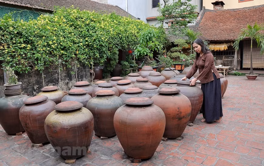 Dès la petite porte d’entrée de l’ancienne maison en latérite de Hà Huu Thê, on sent déjà l’odeur fermentée de la sauce soja. Dans une grande cour de 50 m², une dizaine de jarres de soja sont alignées pour profiter des rayons du soleil. Hà Huu Thê, artisan avec plus de 30 ans d’expériences, réussit à vendre ses produits aux consommateurs étrangers. Il est attaché à ce métier qui se transmet de génération en génération. Et sa famille possède une recette mystérieuse qu’elle conserve prudemment. Cette recette contient du riz gluant, du soja, des haricots verts, de l’eau du puits et du sel. À noter que l’eau utilisée vient des puits profonds de plus de 15m dans le village. Photo: Vietnamplus