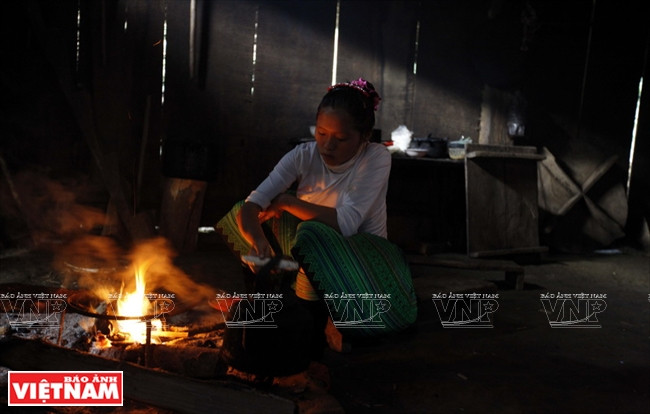 Une femme H’mong dans son habitation en bois.