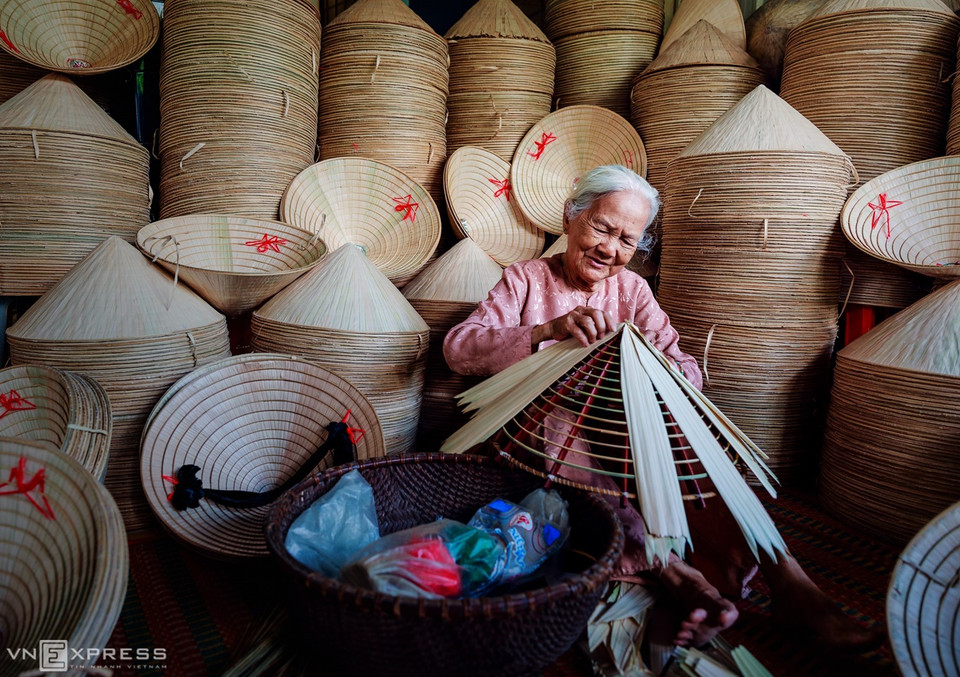 L’auteur a enregistré également la vie quotidienne d'autres villages artisanaux de Tay Ninh. Les chapeaux coniques font partie de la vie des Vietnamiens. Parmi les lieux de production de chapeaux citons le village de Ninh Son (ville de Tay Ninh) et le quartier d'An Hoa (bourg de Trang Bang). Sur la photo, une vieille dame portant une chemise ba ba fait un chapeau dans le quartier de Ninh Son.