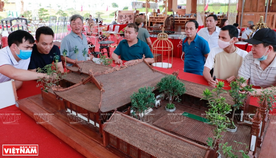  Des visiteurs enthousiastes de découvrir la plus petite maquette de maison commune en bois du Vietnam. Photo : Vietnam Illustré