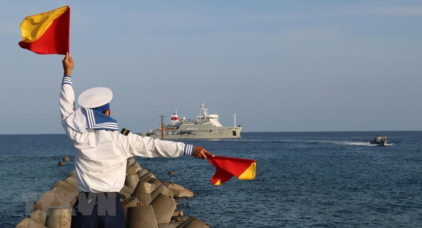 Un soldat de l'île de Song Tu Tay agite les drapeaux pour guider le canoë transportant des officiers et des soldats du navire Truong Sa 571 jusqu'à l'île de Song Tu Tay.