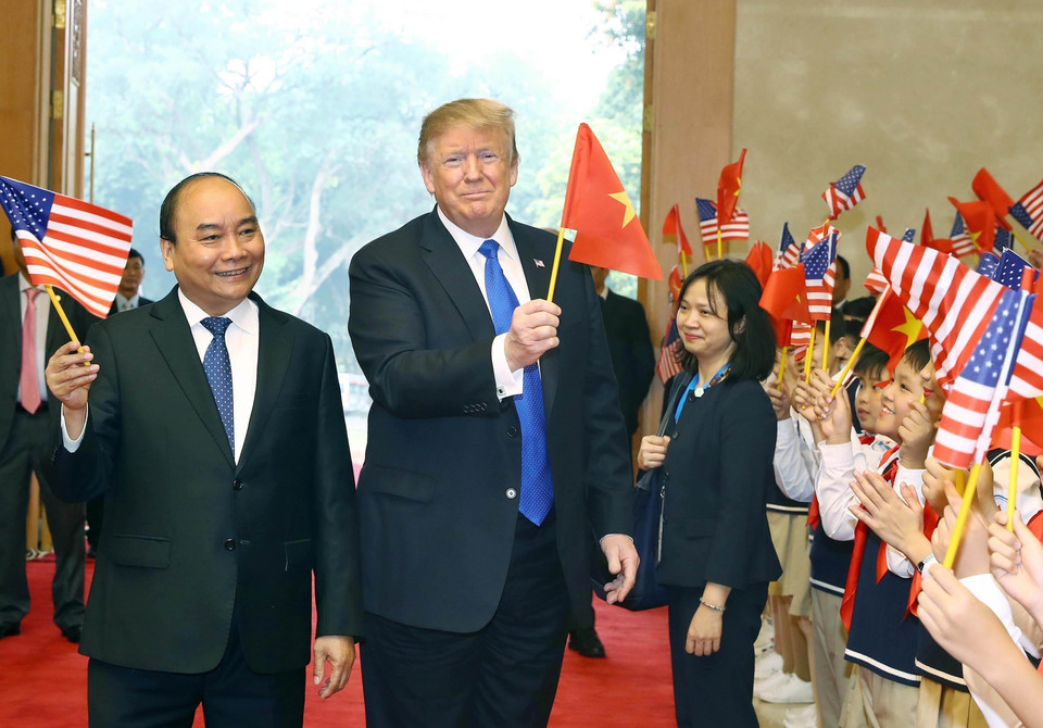 Le Premier ministre Nguyen Xuan Phuc (gauche) et le président américain Donald Trump ont agité les drapeaux des deux pays, lors d'une cérémonie d'accueil organisé le 27 février 2019 au siège du gouvernement vietnamien à l'intention du dirigeant américain. Photo : Thong Nhat – VNA. 