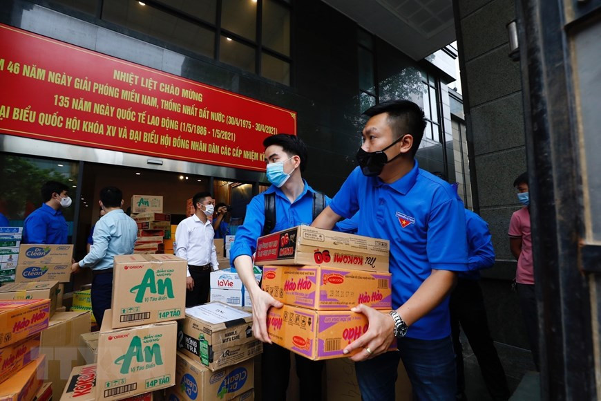 Des membres de l’antenne de l’Union de la jeunesse communiste Ho Chi Minh au sein du bloc des organes du ressort central transportent des biens de première nécessité pour soutenir la province de Bac Giang impactée par le COVID-19. Photo: VNA
