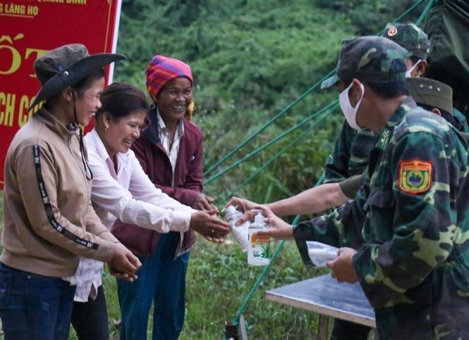 Des gardes-frontières de Quang Binh donnent du gel désinfectant pour les mains à des habitants locaux. Photo: VNA