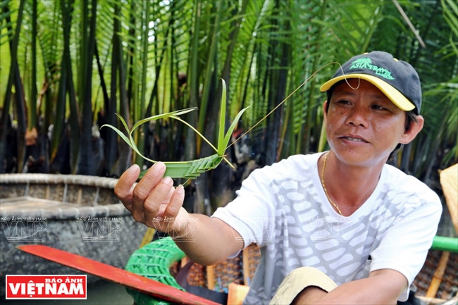 Le guide-rameur de kouffa crée des animaux avec des vieilles feuilles de cocotier en guise de cadeau pour le touriste.