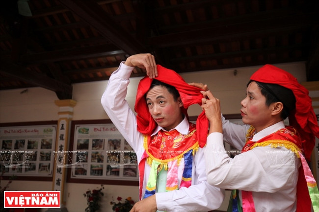 Un danseur aide Cao Anh, qui fait partie de l'équipe de danse du village de Triêu Khuc depuis plus de 10 ans, à se ceindre la tête d’un fanchon. 