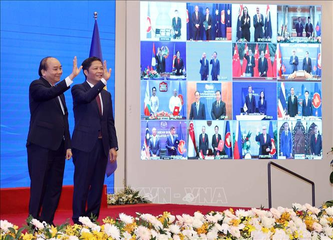 Le Premier ministre Nguyen Xuan Phuc (gauche), le ministre de l'Industrie et du Commerce Tran Tuan Anh et les dirigeants des pays participent à la signature du RCEP sous forme en ligne. 