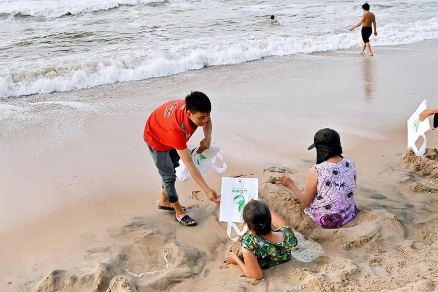 Des volontaires offrent des sacs respectueux de l'environnement aux habitants à la plage de Dôi Duong. Photo: VNA