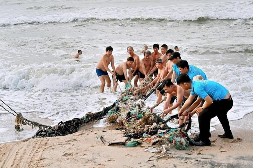 Des habitants et des volontaires ramassent des déchets à la plage de Dôi Duong. Photo: VNA