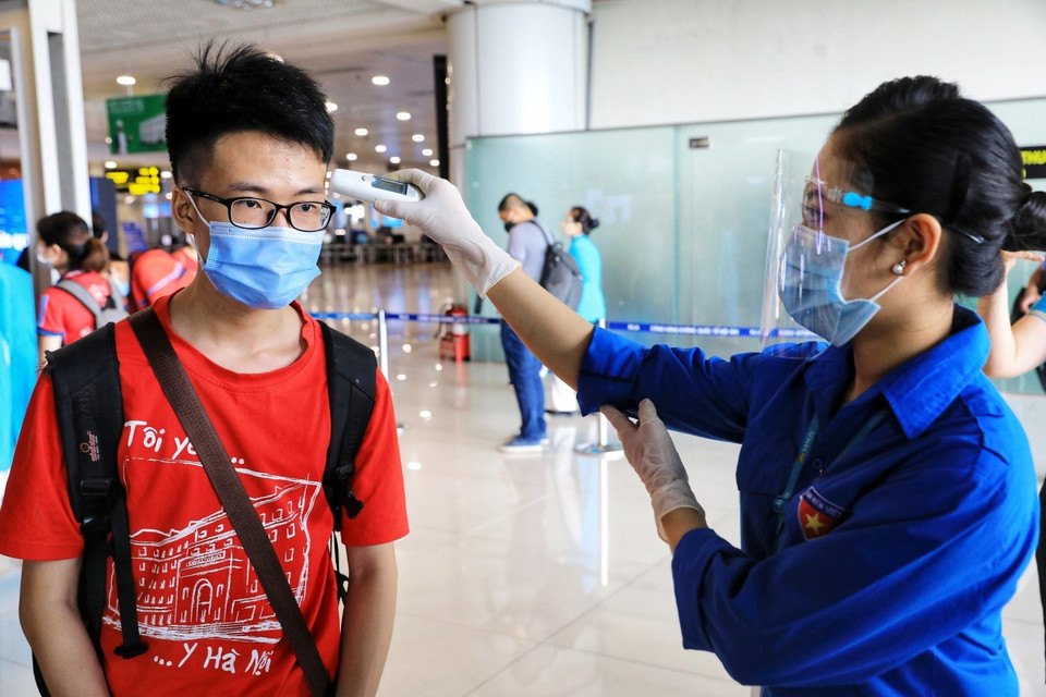 Le personnel de l'aéroport de Noi Bai vérifie la température corporelle pour 350 étudiants et professeurs de l'Université de Médecine de Hanoï avant l'heure d'embarquement. Photo: VNA