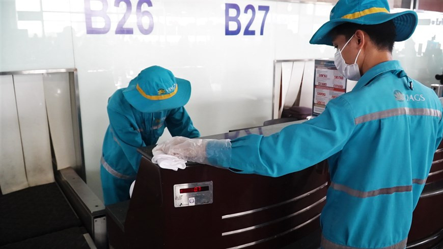 Le personnel de nettoyage désinfecte les comptoirs d'enregistrement avant d'accueillir les clients.