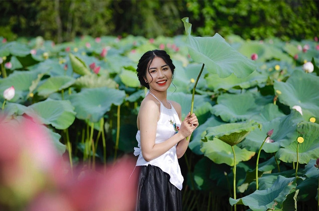 Une fille pose pour une photo à l'étang de lotus.