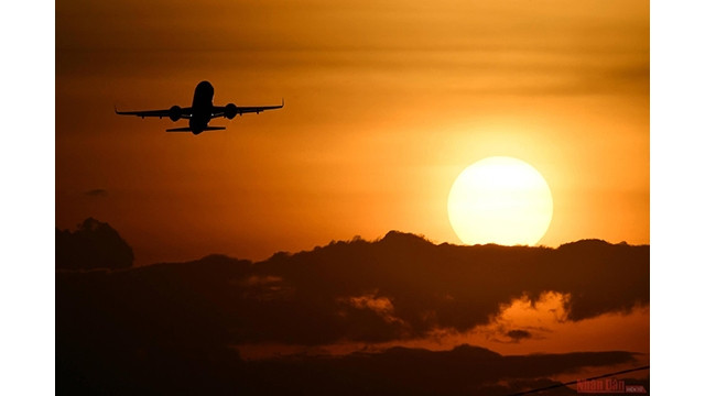 Un avion décolle à l'aéroport international de Nôi Bài au coucher du soleil, créant un paysage poétique à la périphérie de Hanoi.