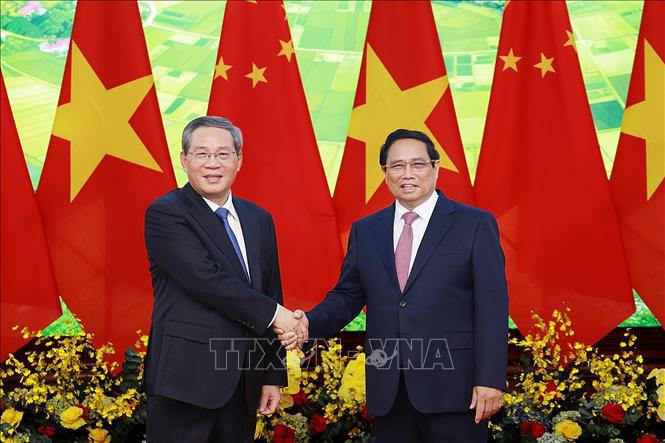 Le Premier ministre Pham Minh Chinh (à droit) et son homomogue chinois Li Qiang se serrent la main. Photo: VNA